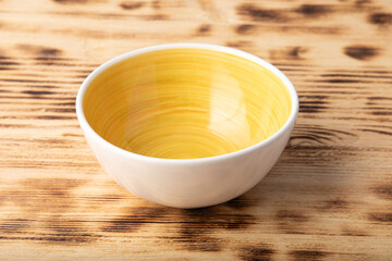 Empty white bowl with hand painted yellow inside. Isolated on wooden background