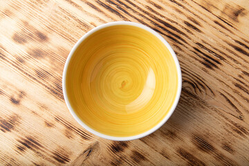 Empty white bowl with hand painted yellow inside. Isolated on wooden background