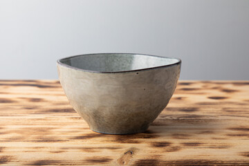 Empty hand made light gray bowl. Isolated on wooden background