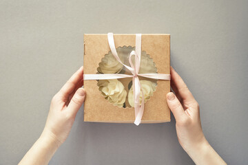 Paper box with cream cupcake. Birthday sweet bakery. Cookies four pack. Yummy buttercream dessert. Wedding party food. Grey background. Holiday recipe. Hand holding