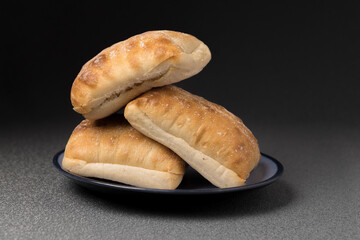 Three ciabatta rolls stacked on plate.