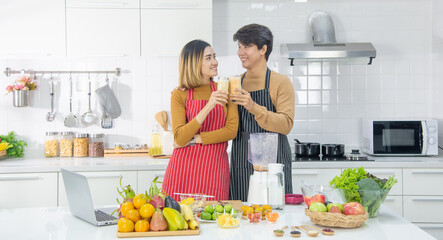 Young beautiful couple in kitchen. Family of two preparing food. Couple making delicious fresh salad. Happy couple preparing healthy vegetarian breakfast with fruits and vegetables
