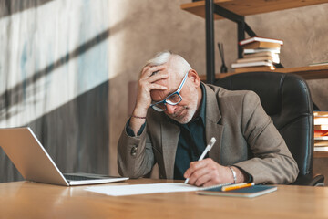 Sign a will. The senior man clings to his head in despair and signs the document. Financial...