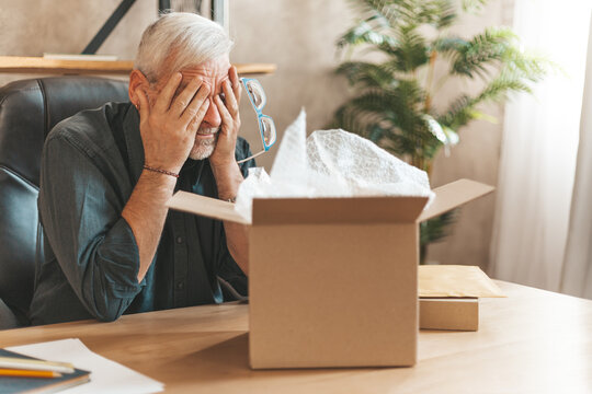Damaged parcel box. Upset mature man closes his eyes, returns the goods to the store. A disgruntled online shopper. Broken item, delivery problem.