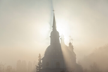 Silhouette of an Orthodox church illuminated by the sun in the morning fog