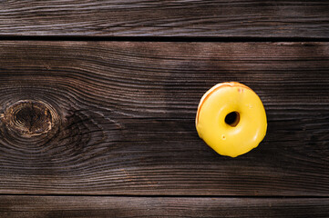 bright yellow donut with banana filling on a wooden table, top view, place for text