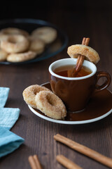 Close up of a cup of tea served with mini sugar and cinnamon donuts.