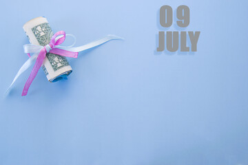 calendar date on blue background with rolled up dollar bills pinned by blue and pink ribbon with copy space. July 9 is the ninth day of the month