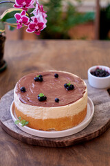 Cake pigeon's milk. Sponge cake and tender soufflé, creamy mousse. Garnished with milk chocolate and blueberries. Side view, wooden background and home flowers.