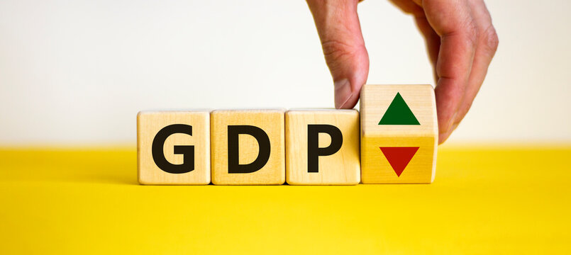 GDP, gross domestic product symbol. Businessman holds a cube with up and down icon. Word 'GDP'. Beautiful white background. Copy space. Business and growth of GDP, gross domestic product concept.