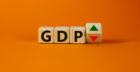 GDP, gross domestic product symbol. Wooden cubes with up and down icon. Word 'GDP'. Beautiful orange background. Copy space. Business and growth of GDP, gross domestic product concept.