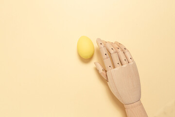 Easter egg. Wooden hand holds a decorative egg on a yellow background. Flat lay. 