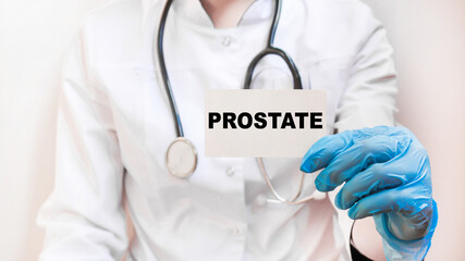 The doctor's blue - gloved hands show the word PROSTATE - . a gloved hand on a white background. Medical concept. the medicine