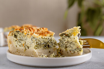 Piece of the traditional French quiche Lorraine pie with feta cheese and spinach served in plate ready to eat. Close-up.