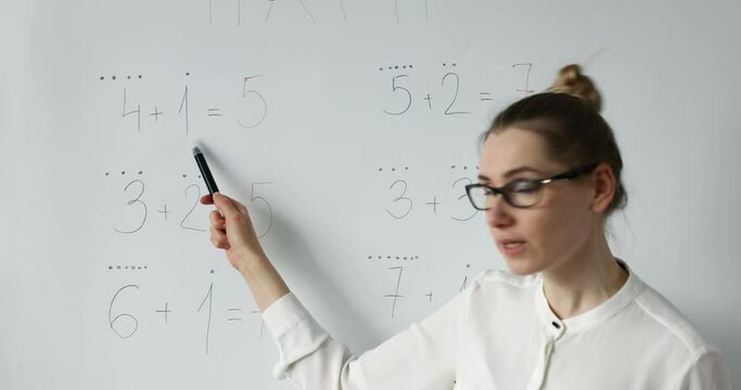 math teacher explaining primary school basic mathematics on whiteboard in classroom