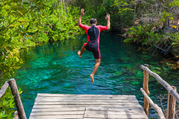 man jumping into a cenote in cancun - obrazy, fototapety, plakaty