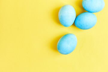 Happy Easter concept. Chicken eggs painted in blue color in the egg compartment. Preparation for holiday. Yellow background copy space