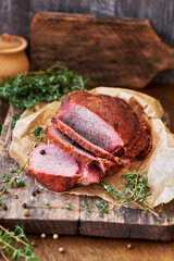 Baked meat with thyme on a wooden board. Wooden background. Rustic style. Side view. Beef, pork.