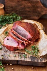 Baked meat with thyme on a wooden board. Wooden background. Rustic style. Side view. Beef, pork.