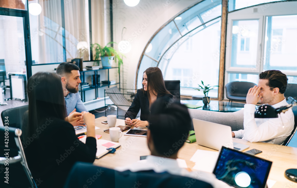 Wall mural Cheerful businesswoman talking with colleagues in modern office