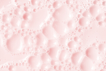 Foamed surface of pink liquid soap, small bubbles, closeup