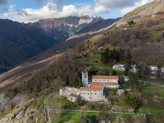 Fototapeta na wymiar Vista aerea della Pieve della Cappella o Pieve di San Martino si trova nel borgo ad Azzano, a Seravezza (LU): si dice che il suo rosone venne costruito da Michelangelo. Sullo sfondo il monte Altissimo