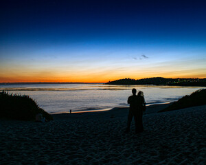 The sun setting over the horizon at a beach in Carmel Ca.