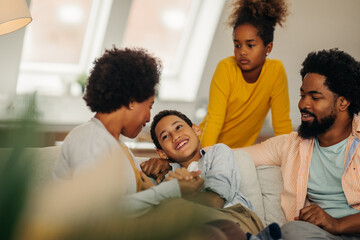 Afro parents and their children are socializing while sitting on the sofa in the living room