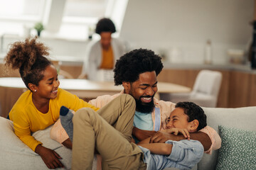 Afro children is having fun with their father in the cozy of their living room