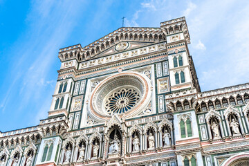 Fototapeta premium Close up on the façade of the Santa Maria del Fiore church or Florence Cathedral in neo-gothic style with white, green and red marbles, statues, niches and a rose window. 