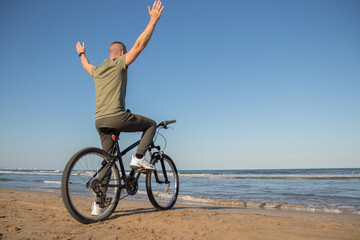 Boy with green shirt and mask arriving at his destination after a bike ride to rest on the beach