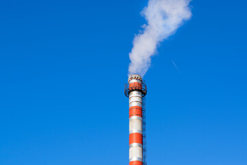Factory chimney releasing steam against the blue sky