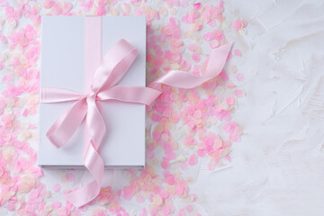 Holiday white background with gift, white box with pink ribbon on pink confetti. Valentine's Day, Happy Women's Day, Mother's Day, Birthday