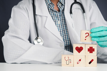 A doctor holding wooden blocks with icons of health and doctor. Close-up photo. Space for text. Concept of doctor and healthcare