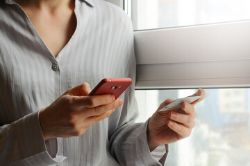 a woman makes purchases online using a mobile phone and a bank credit card. online shopping from home