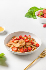 Trendy breakfast with mini pancakes and strawberry on white.