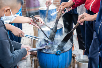 Children use tongs to dip tie-dye cloth into a pot in Chiangmai, Thailand