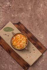 Homemade sauerkraut with carrots in a deep plate on a rustic background. Fermented product.