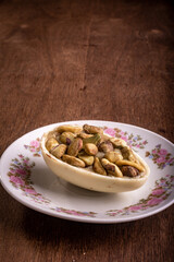 Mini stuffed white chocolate with pistachio easter egg on a white plate with flower design on a wooden table.