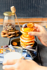 pancakes with a sweet plum and honey in a frying pan on a blue wooden background. a glass of milk.comfort food concept