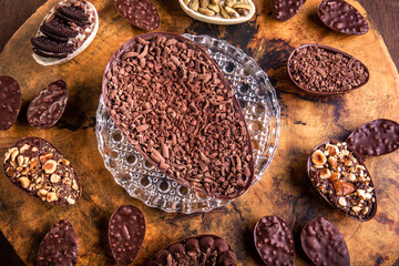 Top view of a stuffed chocolate easter egg with grated chocolate on the top and lots of mini stuffed easter eggs all around it on a tree trunk.