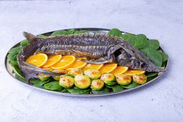 Sterlet baked (Sturgeon) with spinach, oranges and Brussels sprouts. Russian cuisine. Close-up.