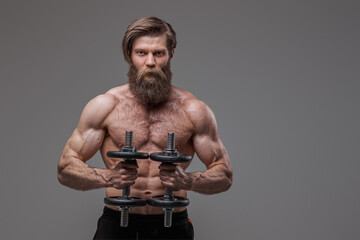 Fototapeta na wymiar Athletic man with fashionable hairstyle and dumbells in studio