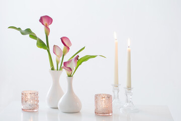 pink calla lily in vase  and burning candles on white background