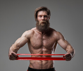 Cool and stylish bodybuilder poses with resistance bands in studio