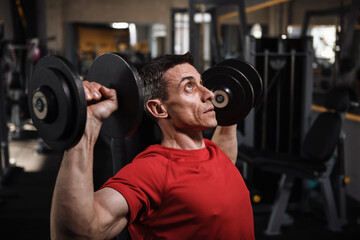 Close up of a mature athletic man exercising with dumbbells