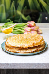 Pancakes with honey on a background of tulip flowers.