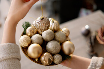 Christmas balls for the tree. Preparing for the new year. Winter holidays concept. The girl holds a golden ball in her hand.