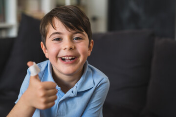 happy young boy holding his injured and bandaged thumb up. he is smiling