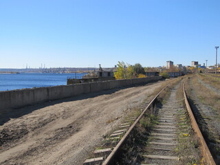 Rural Railway. old railroad with rusty rails running along the riverbank